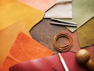 Leather craft. Colorful pieces of beautifully colored or tanned leather and leather working tools on leather craftman's work desk .